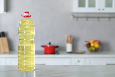 Photo of Bottle of cooking oil on white marble table in kitchen. Space for text