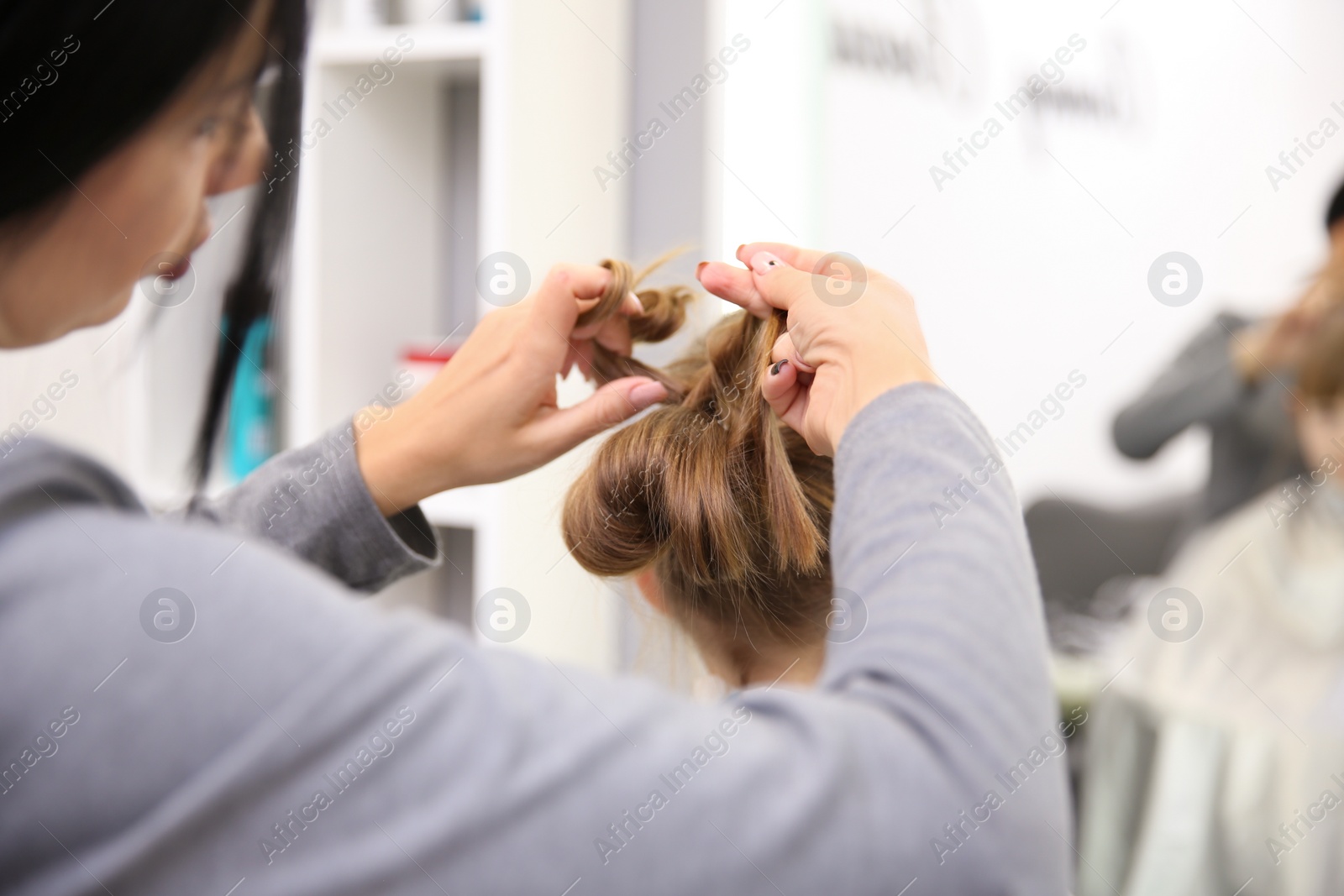 Photo of Professional female hairdresser working with little girl in salon