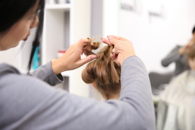 Professional female hairdresser working with little girl in salon