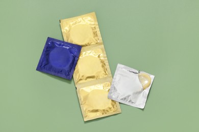 Photo of Packaged condoms on light green background, top view. Safe sex