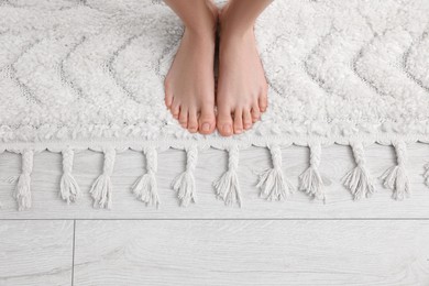 Woman standing on soft white carpet at home, top view