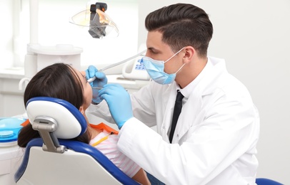 Photo of Professional dentist working with patient in clinic