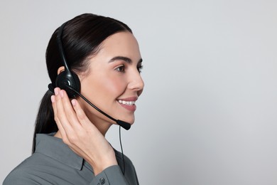 Hotline operator with modern headset on light grey background, space for text. Customer support