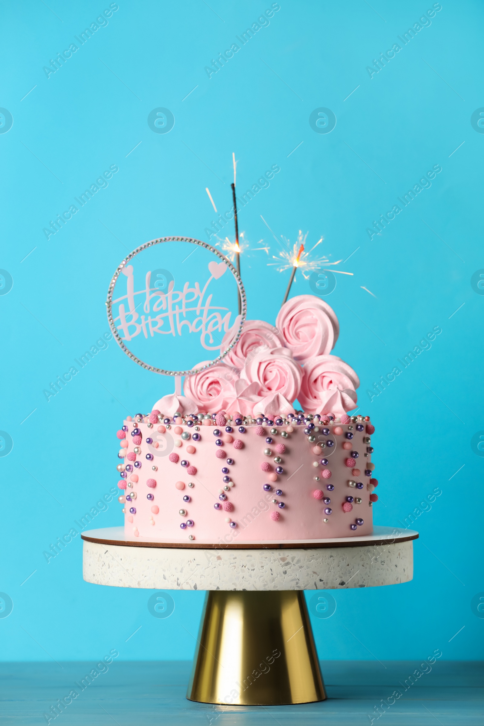 Photo of Beautifully decorated birthday cake with party decor on turquoise wooden table