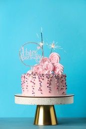 Photo of Beautifully decorated birthday cake with party decor on turquoise wooden table