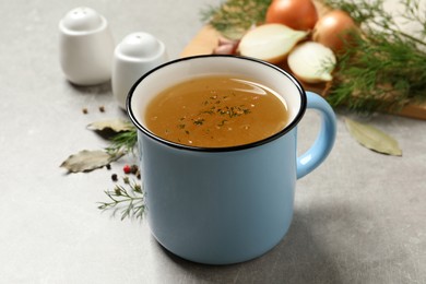 Hot delicious bouillon with dill in cup on light grey table