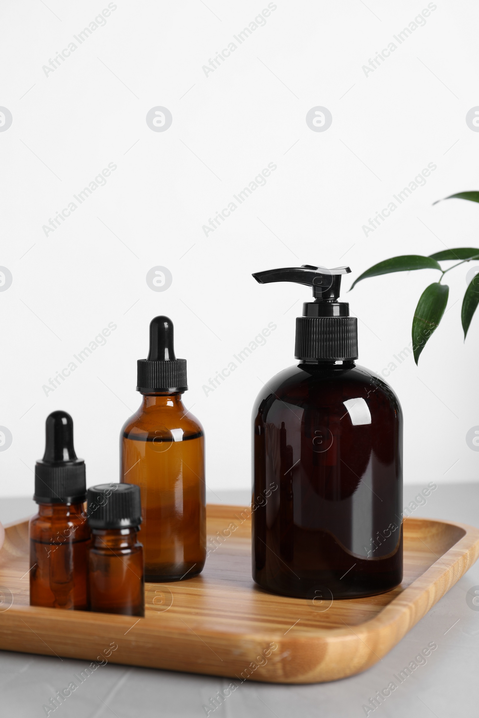 Photo of Different cosmetic products and leaves on grey table