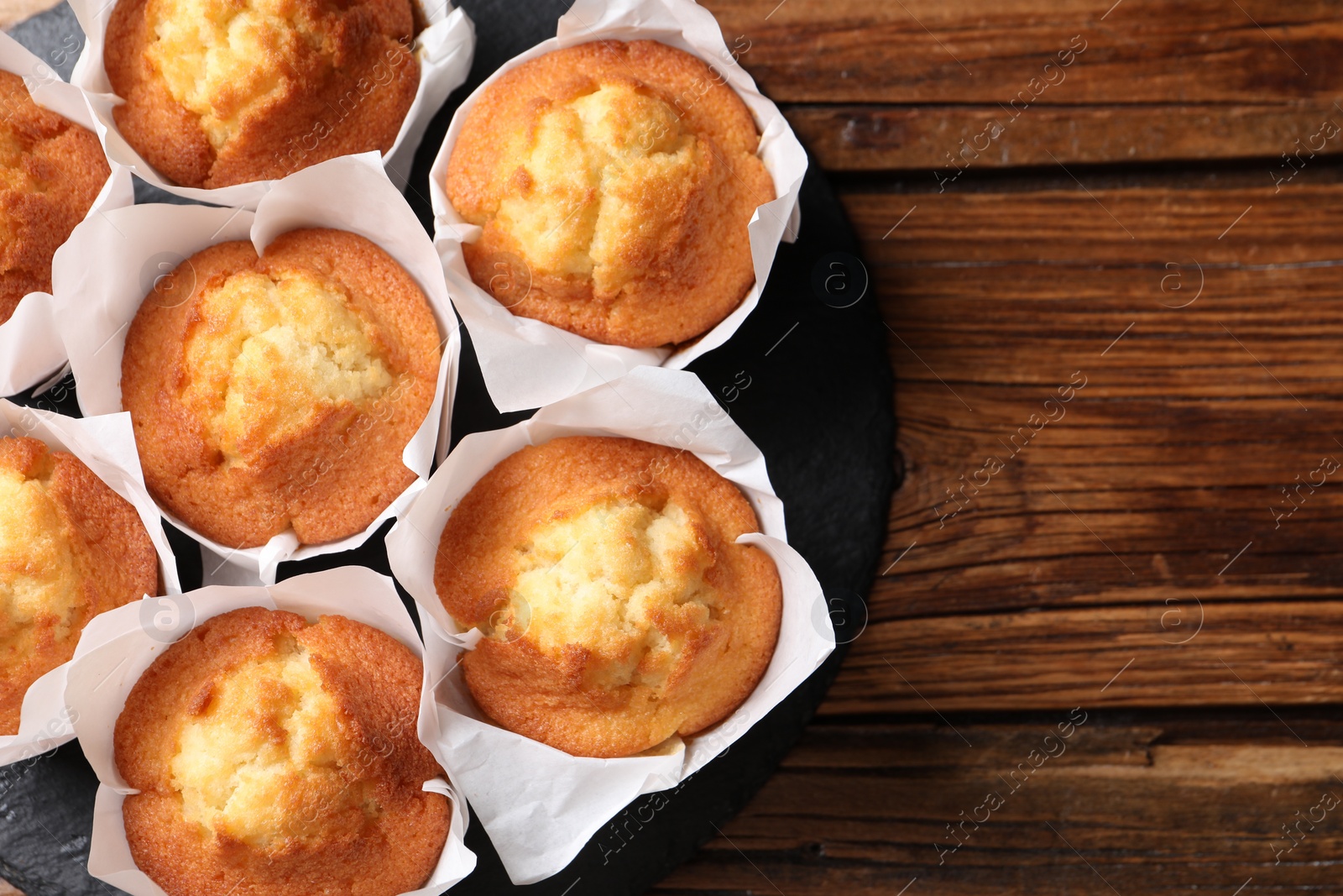 Photo of Delicious sweet muffins on wooden table, top view. Space for text