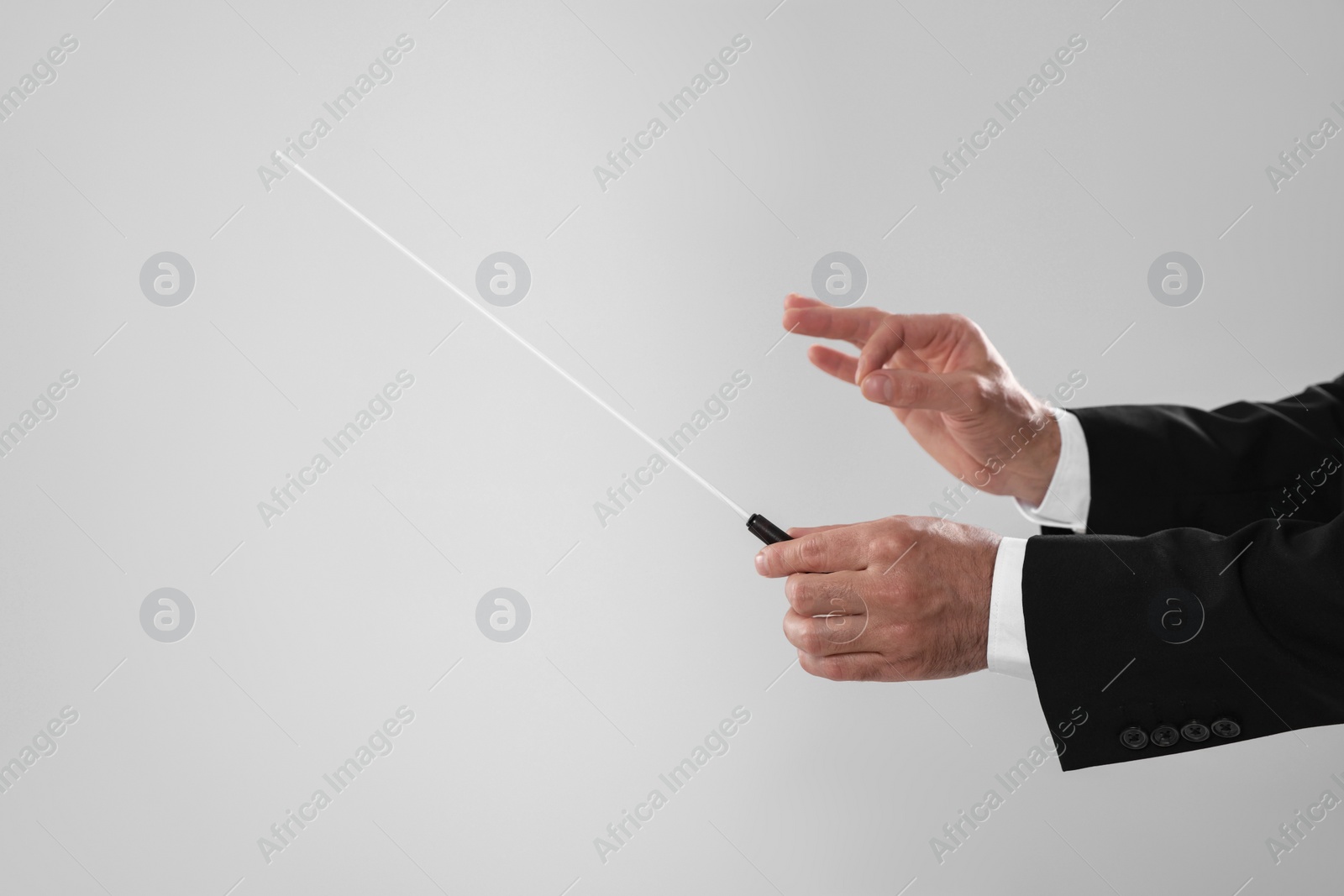 Photo of Professional conductor with baton on light grey background, closeup. Space for text