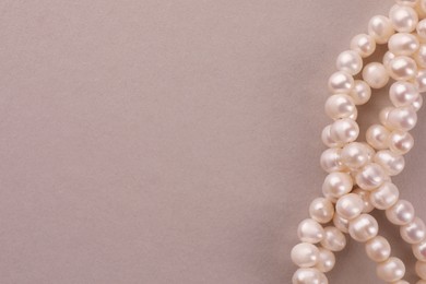 Photo of Elegant pearl necklace on beige background, top view. Space for text