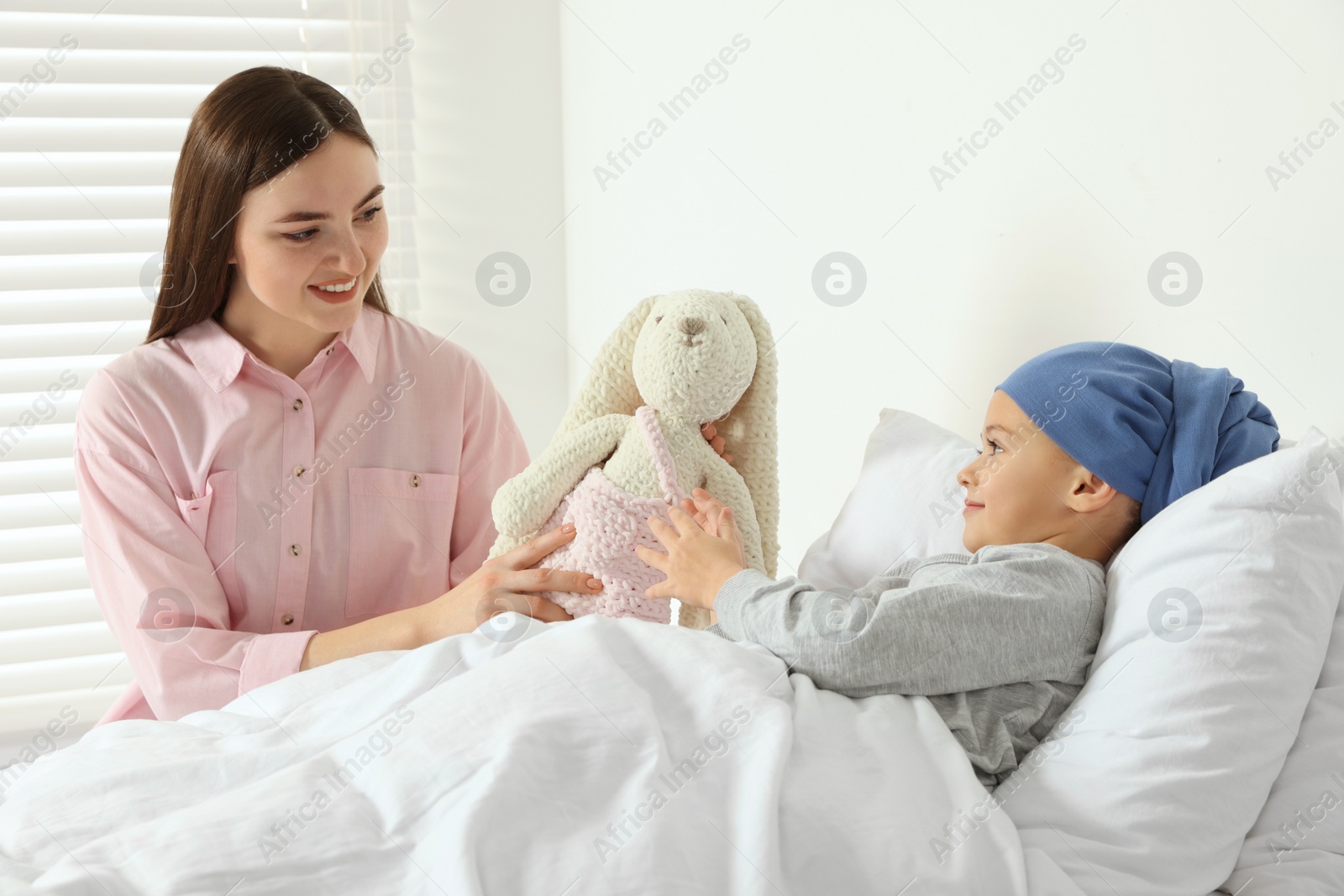 Photo of Childhood cancer. Mother and daughter with toy bunny in hospital