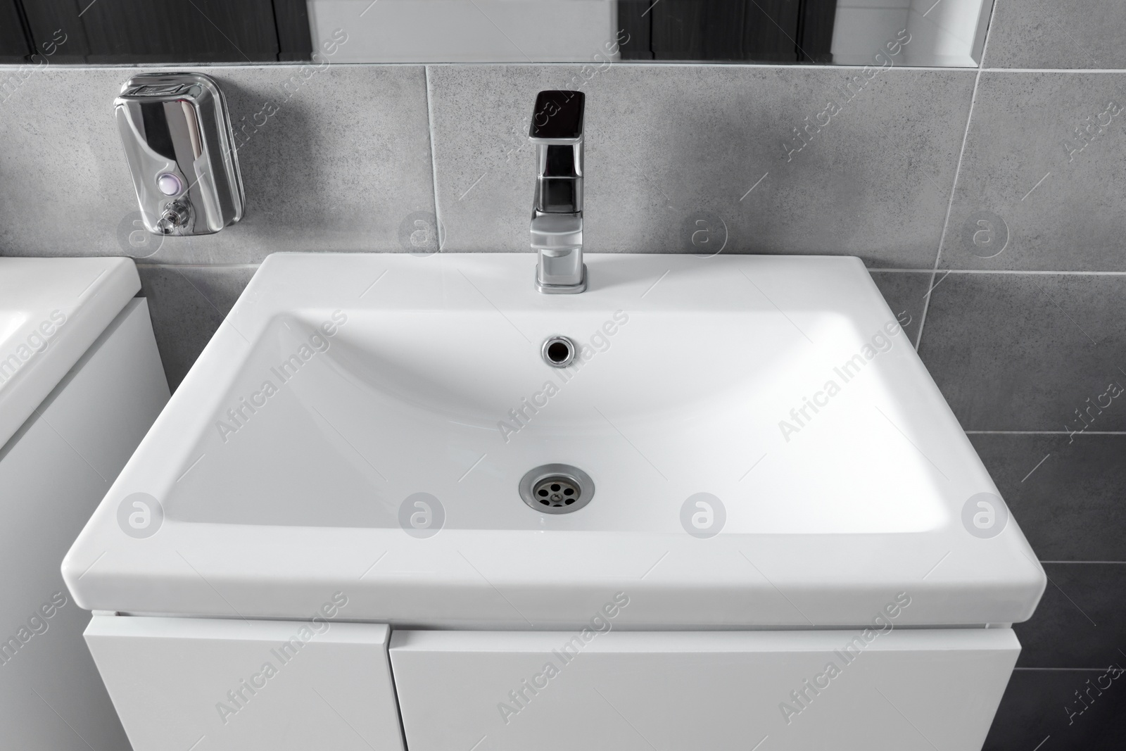 Photo of Beautiful clean sink near mirror in public toilet