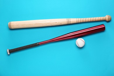 Baseball bats and ball on light blue background, flat lay