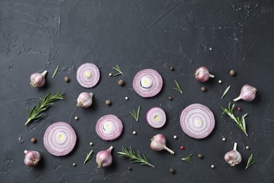 Photo of Fresh raw garlic heads, onion rings and spices on black table, flat lay. Space for text