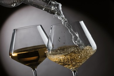 Photo of Pouring tasty aromatic wine in glass on gray background, closeup