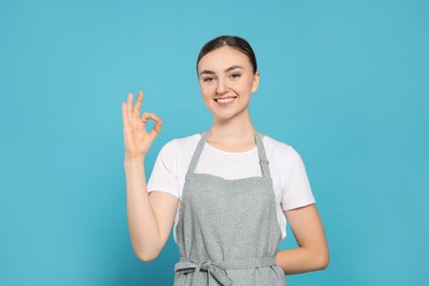 Photo of Beautiful young woman in clean apron with pattern on light blue background