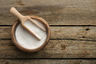 Baking powder in bowl and scoop on wooden table, top view. Space for text