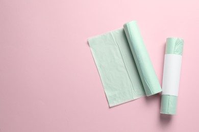 Photo of Rolls of garbage bags on pink background, flat lay. Space for text