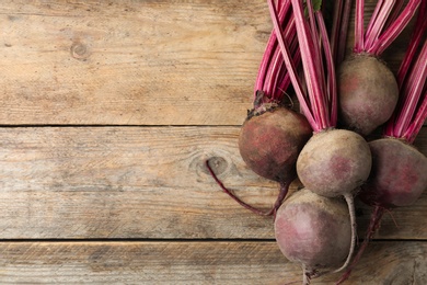 Photo of Raw ripe beets on wooden table, flat lay. Space for text