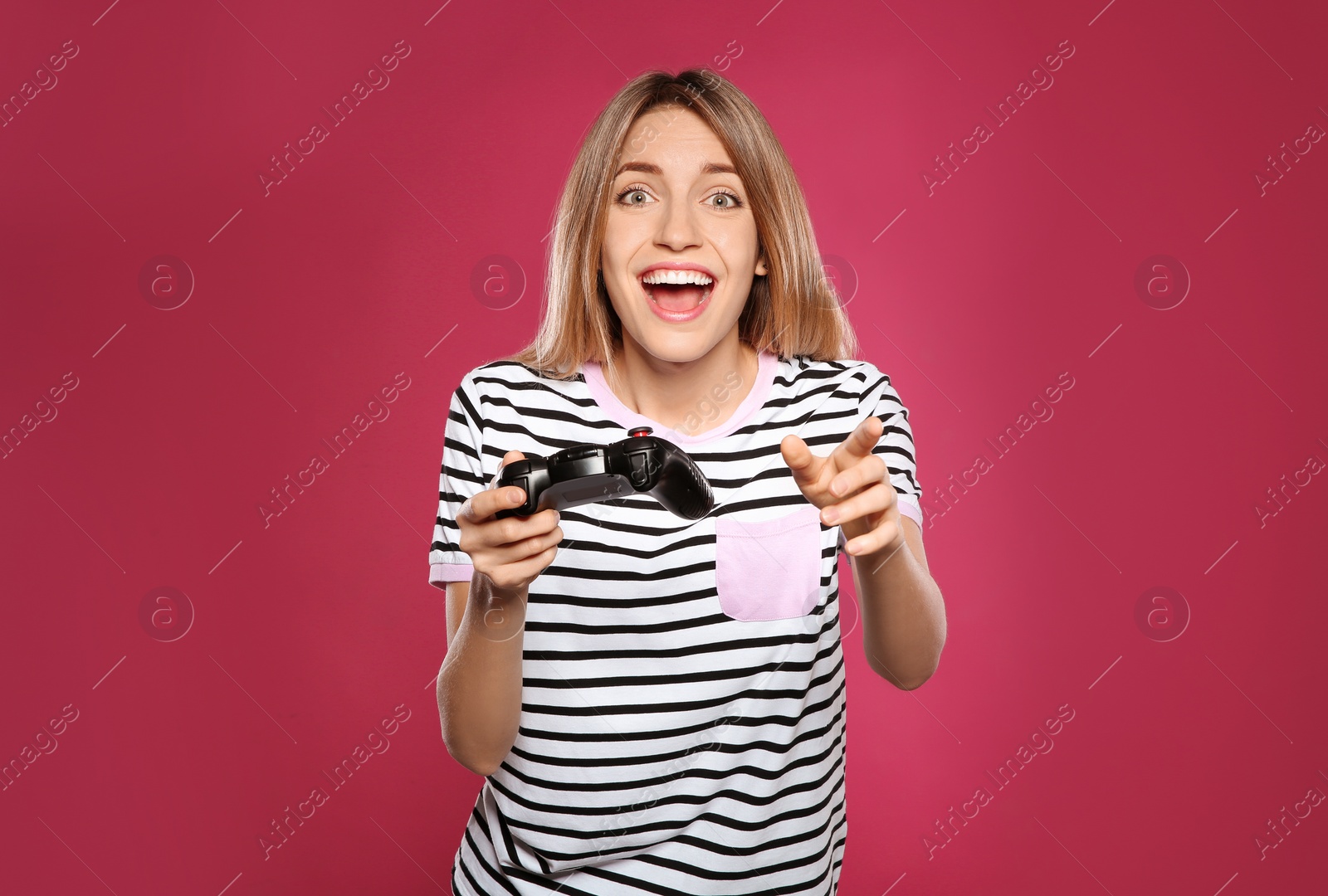 Photo of Emotional young woman playing video games with controller on color background