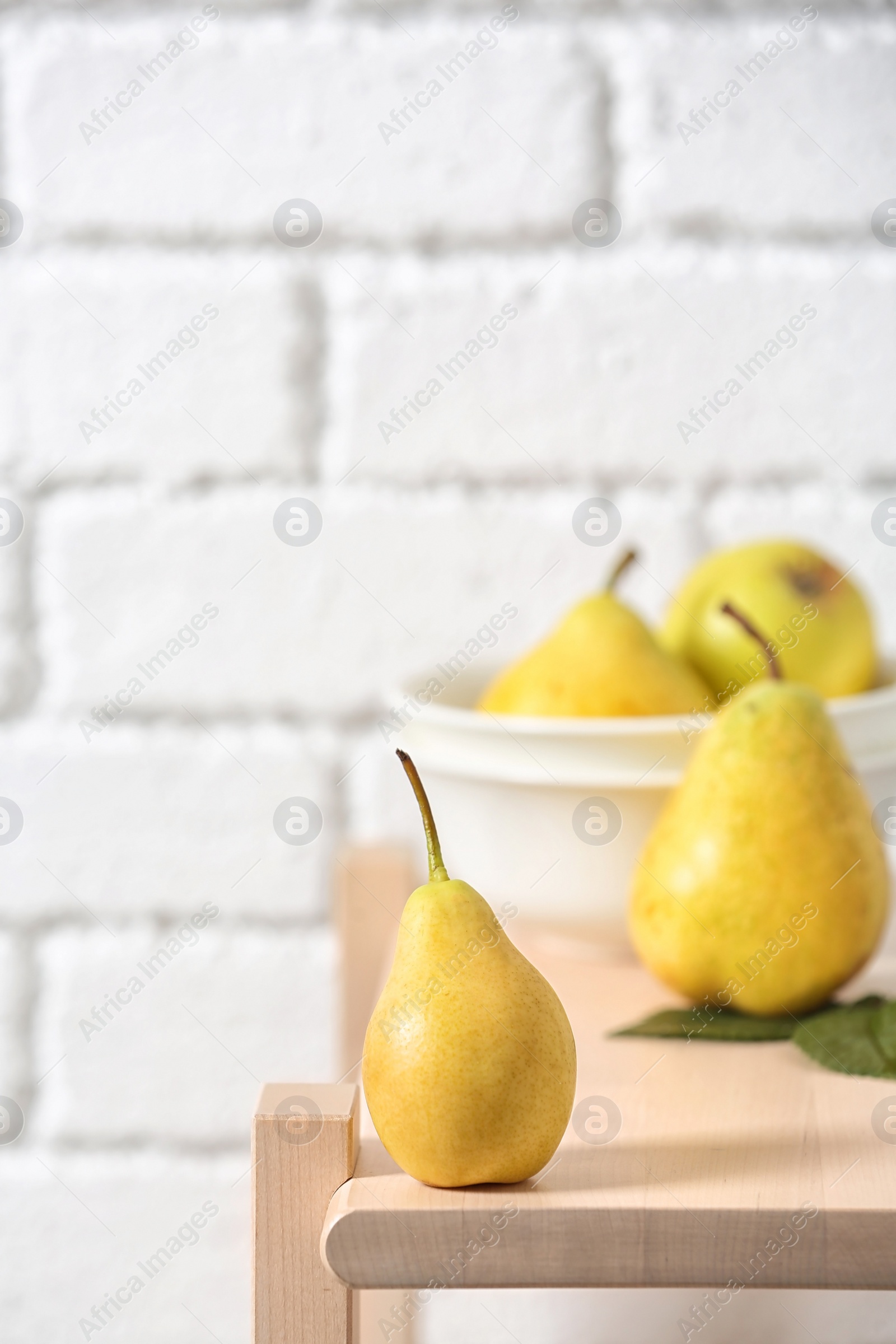 Photo of Ripe pear on wooden shelf against blurred background. Space for text