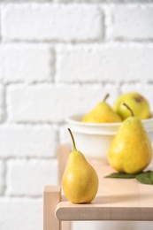 Ripe pear on wooden shelf against blurred background. Space for text