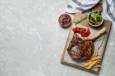 Photo of Delicious grilled ribeye steak served on light grey marble table, flat lay. Space for text