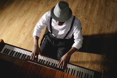 Photo of African-American man playing piano indoors, above view. Talented musician