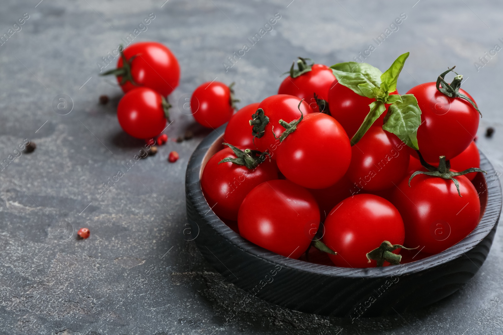 Photo of Fresh ripe cherry tomatoes and basil on grey table, closeup. Space for text