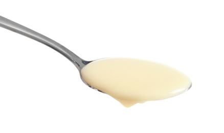 Photo of Spoon with condensed milk on white background, closeup. Dairy product