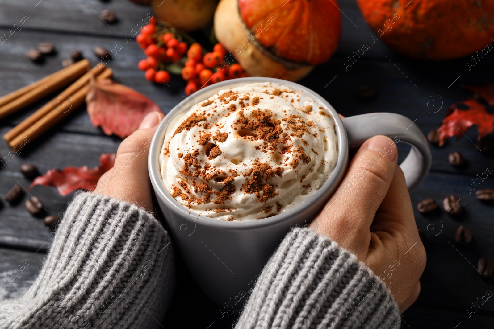 Photo of Woman with cup of tasty pumpkin spice latte at wooden table, closeup