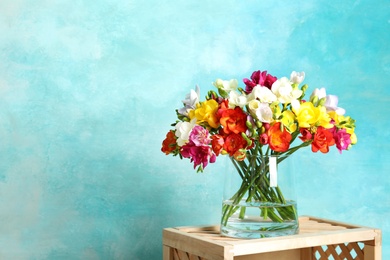 Bouquet of spring freesia flowers in vase on color background. Space for text