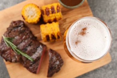 Photo of Glass of beer, delicious fried steak and corn on grey table, top view. Space for text