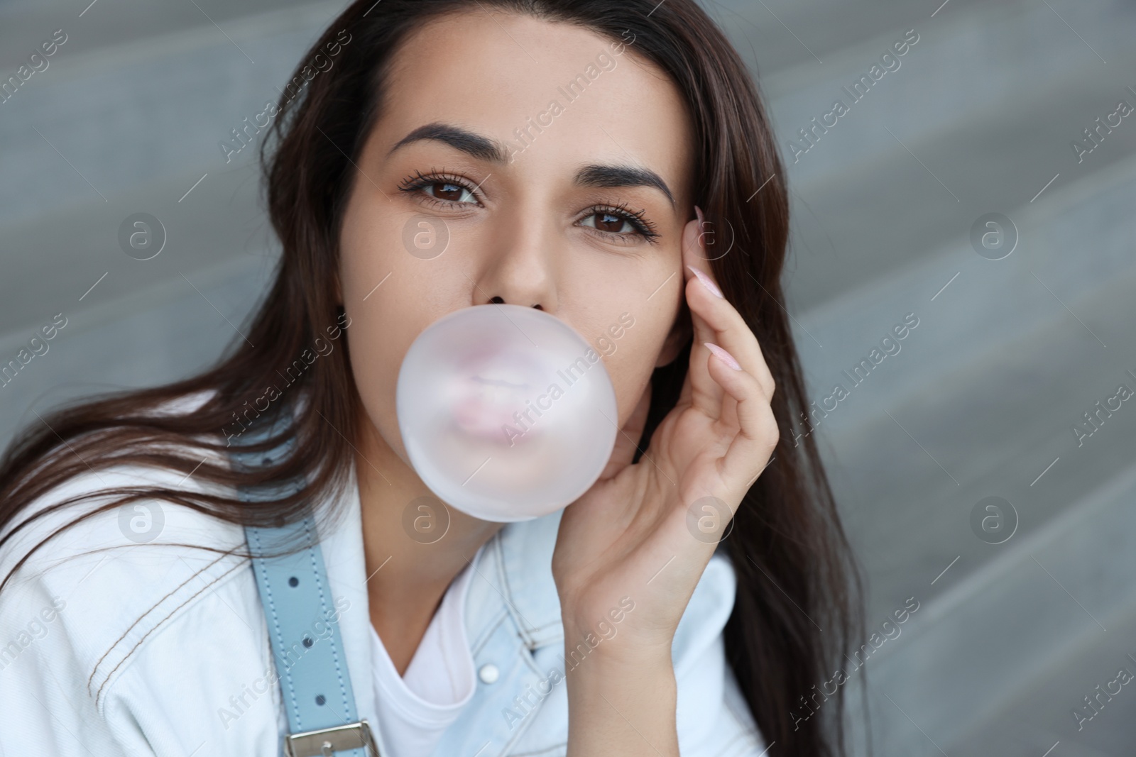 Photo of Stylish woman blowing gum near stairs outdoors, closeup