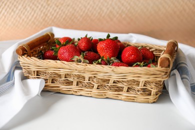 Photo of Wicker basket with ripe strawberries and napkin on white table