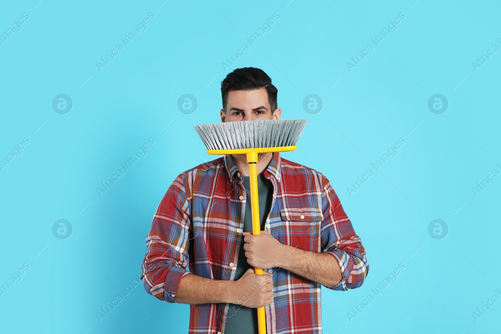 Photo of Man with yellow broom on light blue background