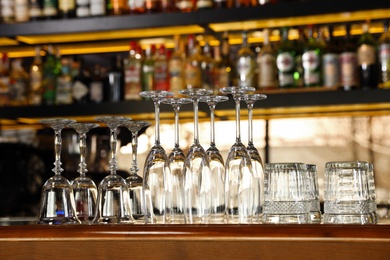 Photo of Different empty clean glasses on counter in bar