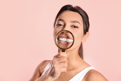 Photo of Young woman with healthy teeth and magnifier on color background