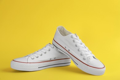 Photo of Pair of stylish sneakers on yellow background