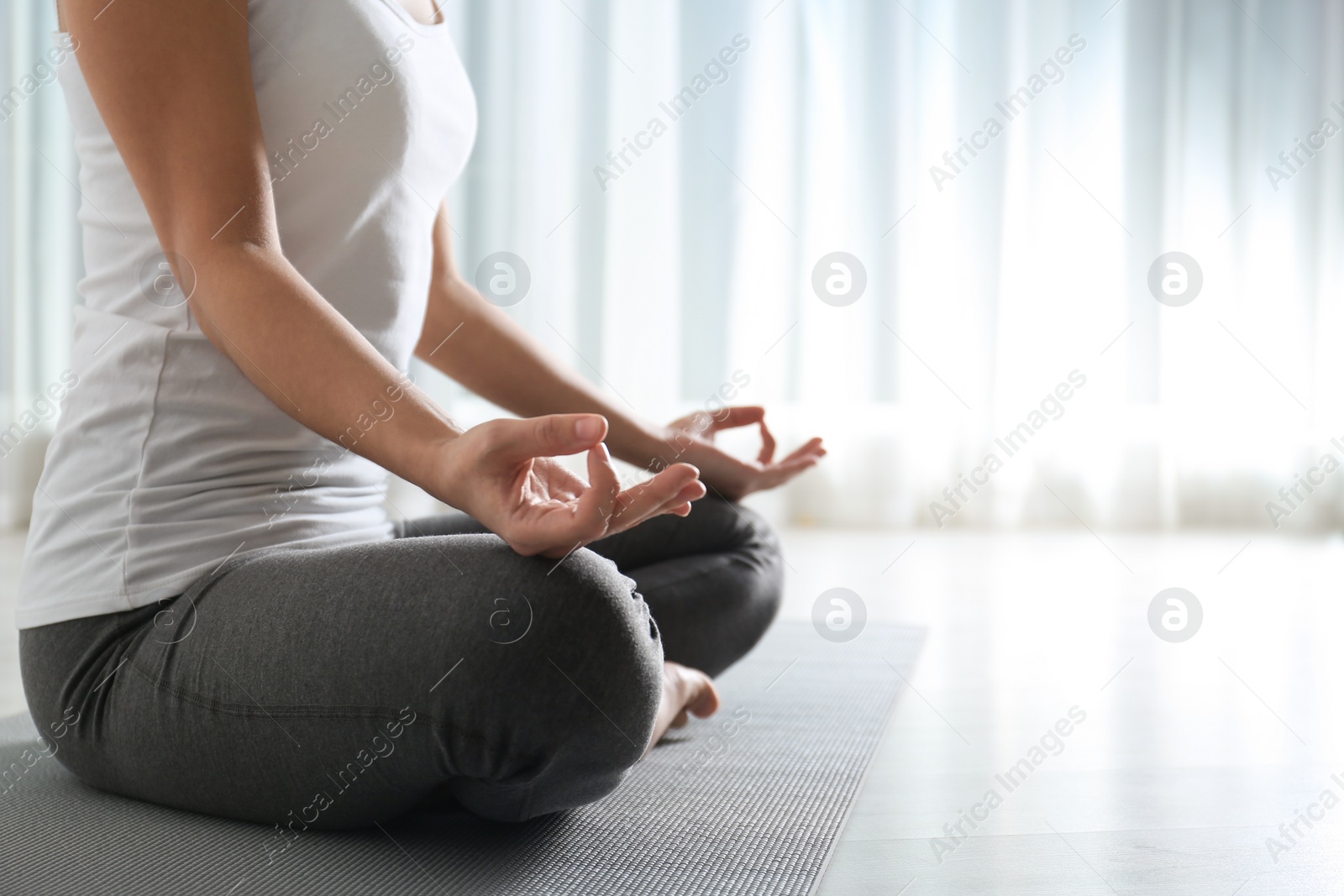 Photo of Woman practicing yoga on floor indoors, closeup. Space for text