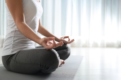 Photo of Woman practicing yoga on floor indoors, closeup. Space for text