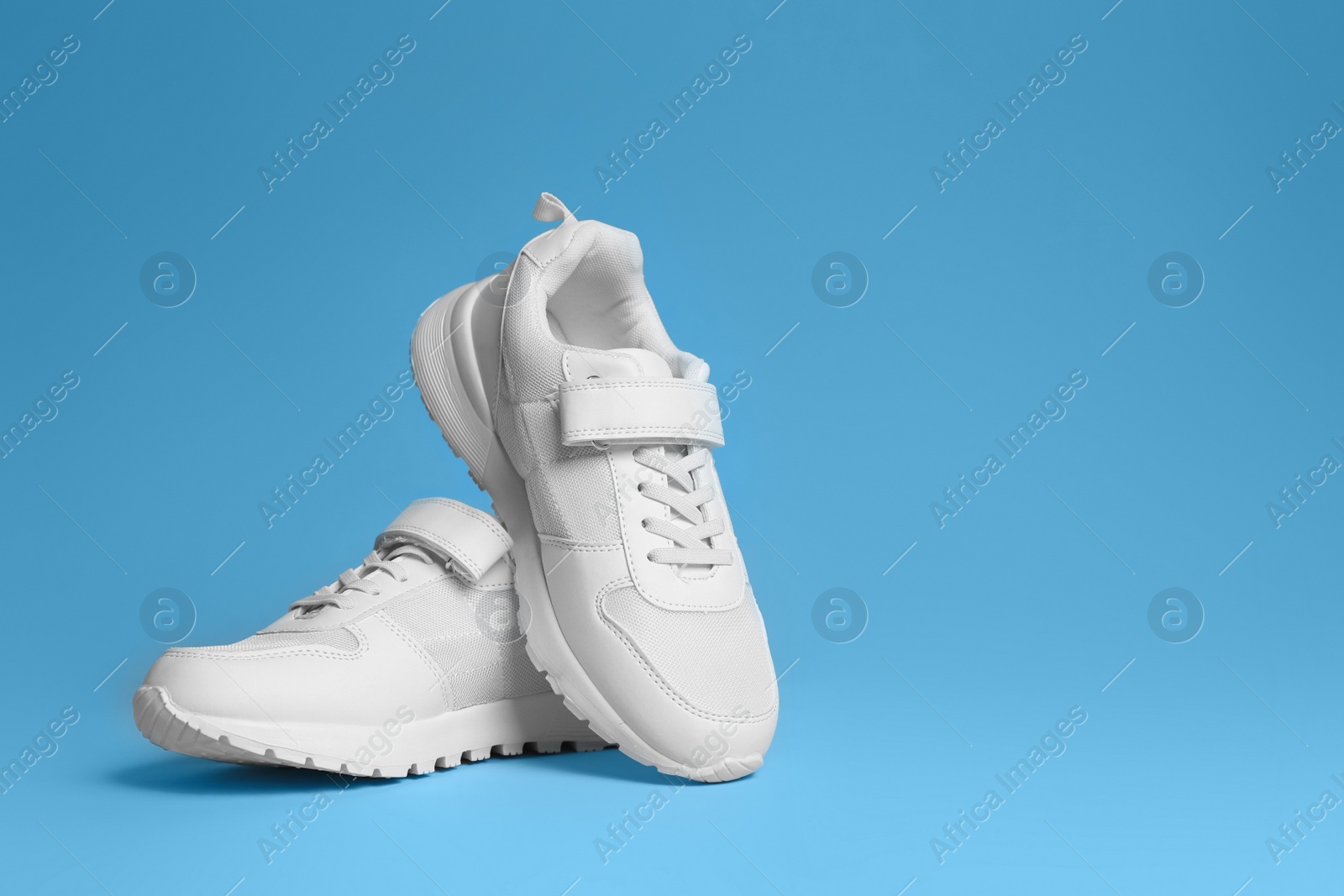 Photo of Pair of stylish sneakers on light blue background. Space for text