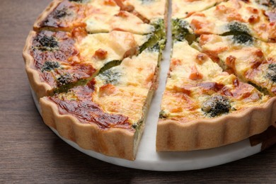 Delicious homemade quiche with salmon and broccoli on wooden table, closeup