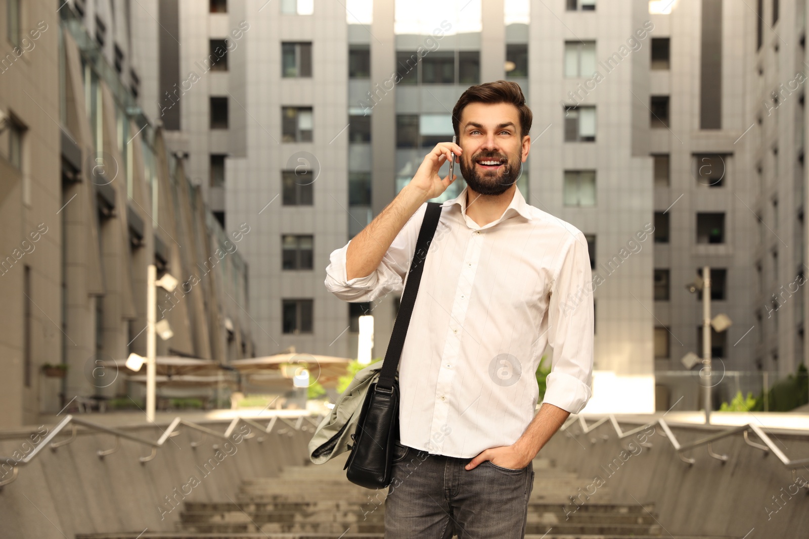 Photo of Handsome man talking on phone in modern city