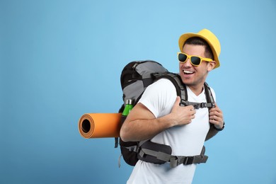 Male tourist with travel backpack on turquoise background, space for text