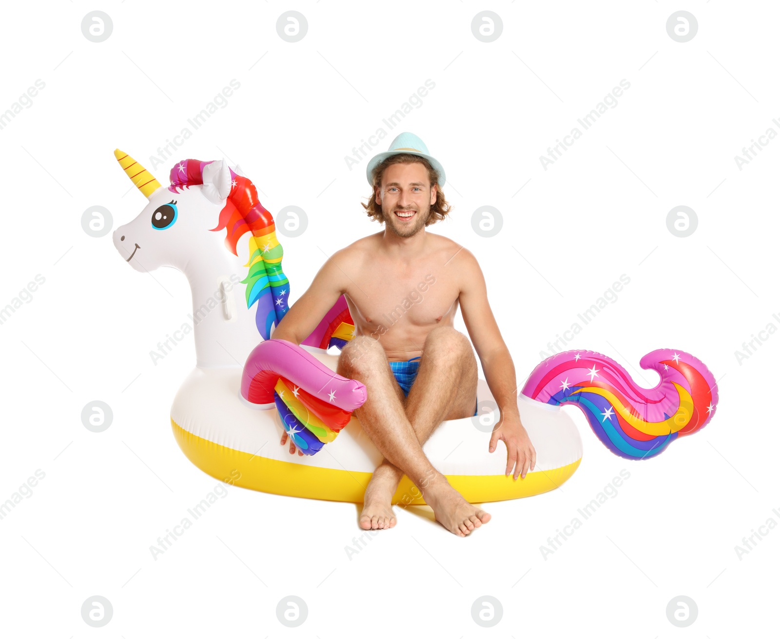 Photo of Attractive young man in swimwear with unicorn inflatable ring on white background