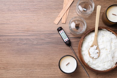 Flat lay composition with homemade candles and ingredients on wooden background, space for text