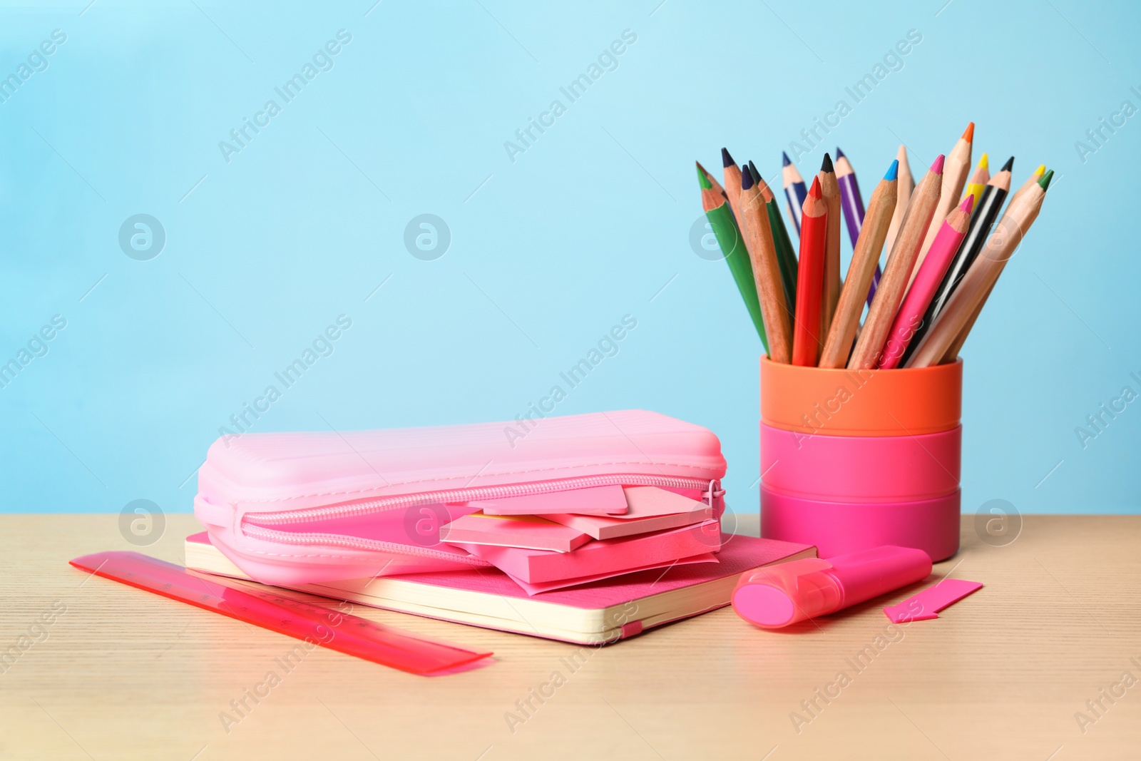 Photo of Composition with different school stationery on wooden table against light blue background. Back to school