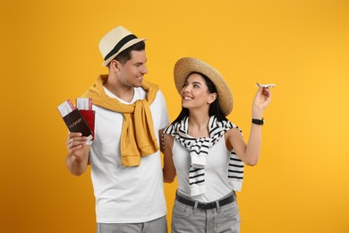 Photo of Couple of tourists with tickets, passports and toy plane on yellow background