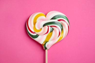 Photo of Stick with heart shaped lollipop on pink background, top view